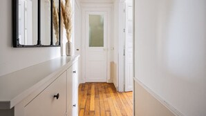Un pasillo con piso de madera, paredes blancas y una puerta blanca al final.