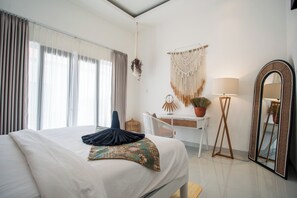Relax in a serene space with a large bed, a desk for work, and a potted plant.