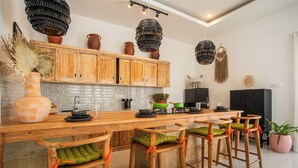 Una cocina moderna con armarios de madera, una encimera larga y taburetes con cojines verdes.
