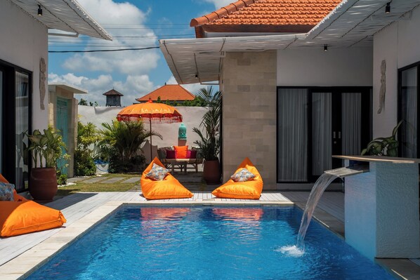 Relax by the clear pool surrounded by comfortable seating and lush greenery.