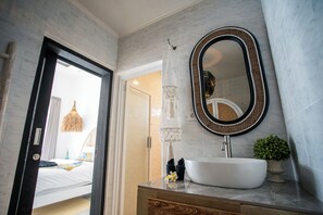 Bathroom features a vessel sink, oval mirror, and a potted plant.