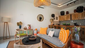 Una sala de estar moderna con sofá, sillas, mesa de comedor y zona de cocina.