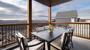 A covered outdoor patio with a table and chairs, overlooking a mountainous landscape. - Lodge 08 - Sweeping views - Resort amenities! (Branson)