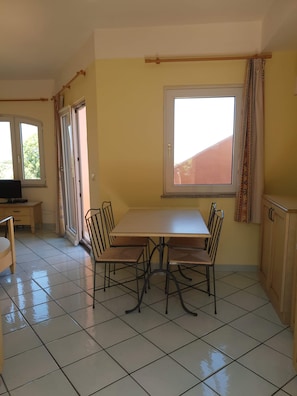 A dining area with a table and chairs, a television, and a window with curtains.