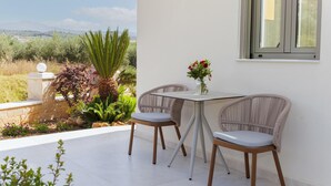 Un patio con una mesa, dos sillas, un jarrón de flores y vistas al paisaje.