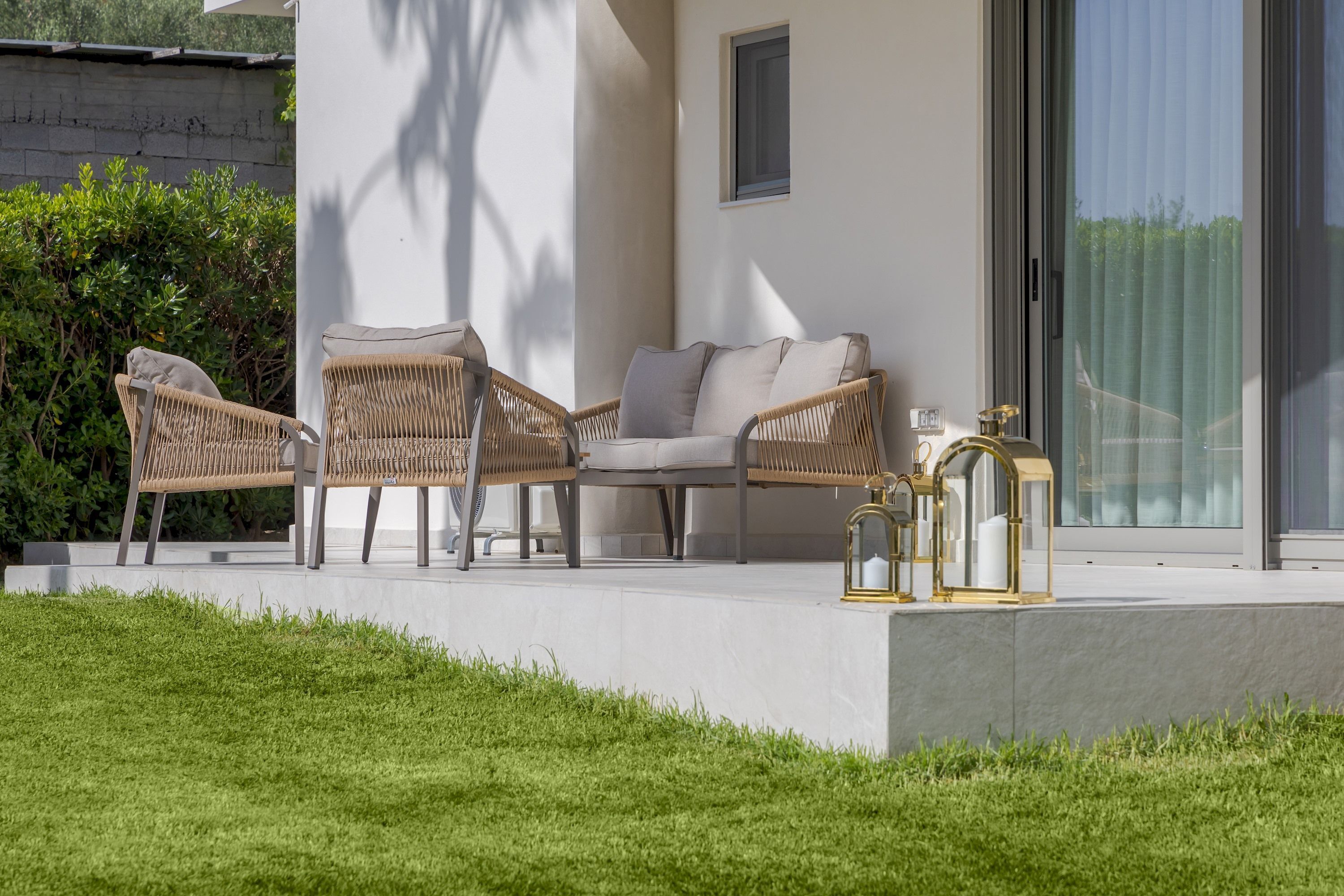 A modern outdoor seating area with wicker furniture and a lantern.