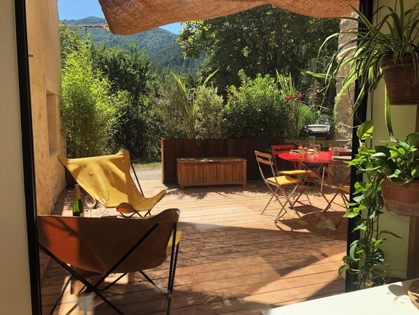 An outdoor patio with a wooden table, chairs, and a wooden bench.