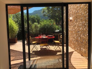 A patio with a table and chairs, a grill, and a view of a mountainous landscape.