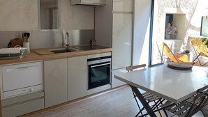 A modern kitchen with a built-in oven, a sink, and a window overlooking a stone wall. - In the heart of the Drôme valley, between Die and Crest,  independent gîte (aurel)