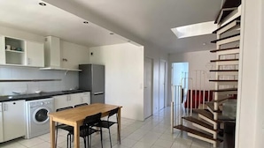 Una cucina moderna con zona pranzo, lavatrice e una scala che conduce a un piano superiore.
