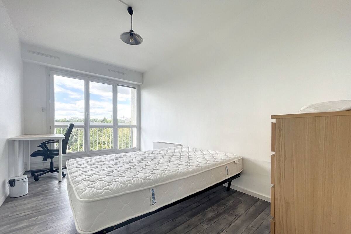 A bedroom with a single bed, a desk, and a chair.