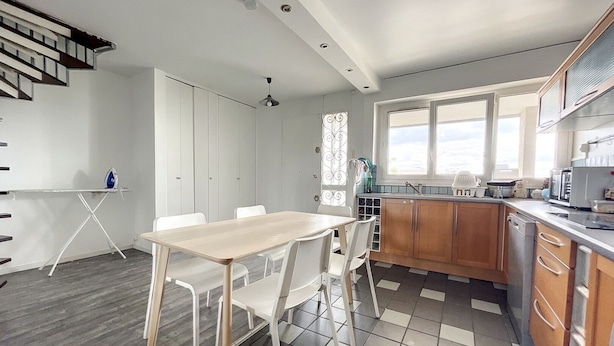 Una cucina moderna con mobili in legno, un'area pranzo con tavolo e sedie, e una scala che conduce a un altro piano.