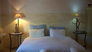 A neatly made bed with white linens, two bedside tables with lamps, and a wall with a textured design.