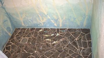 A mosaic floor with a geometric pattern and a painted wall with tree-like designs.