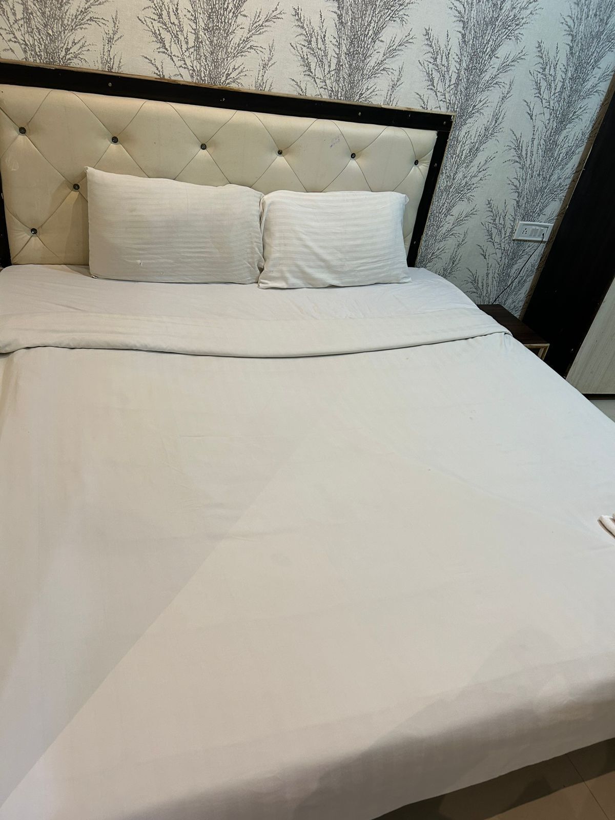 A neatly made bed with a tufted headboard and two pillows.