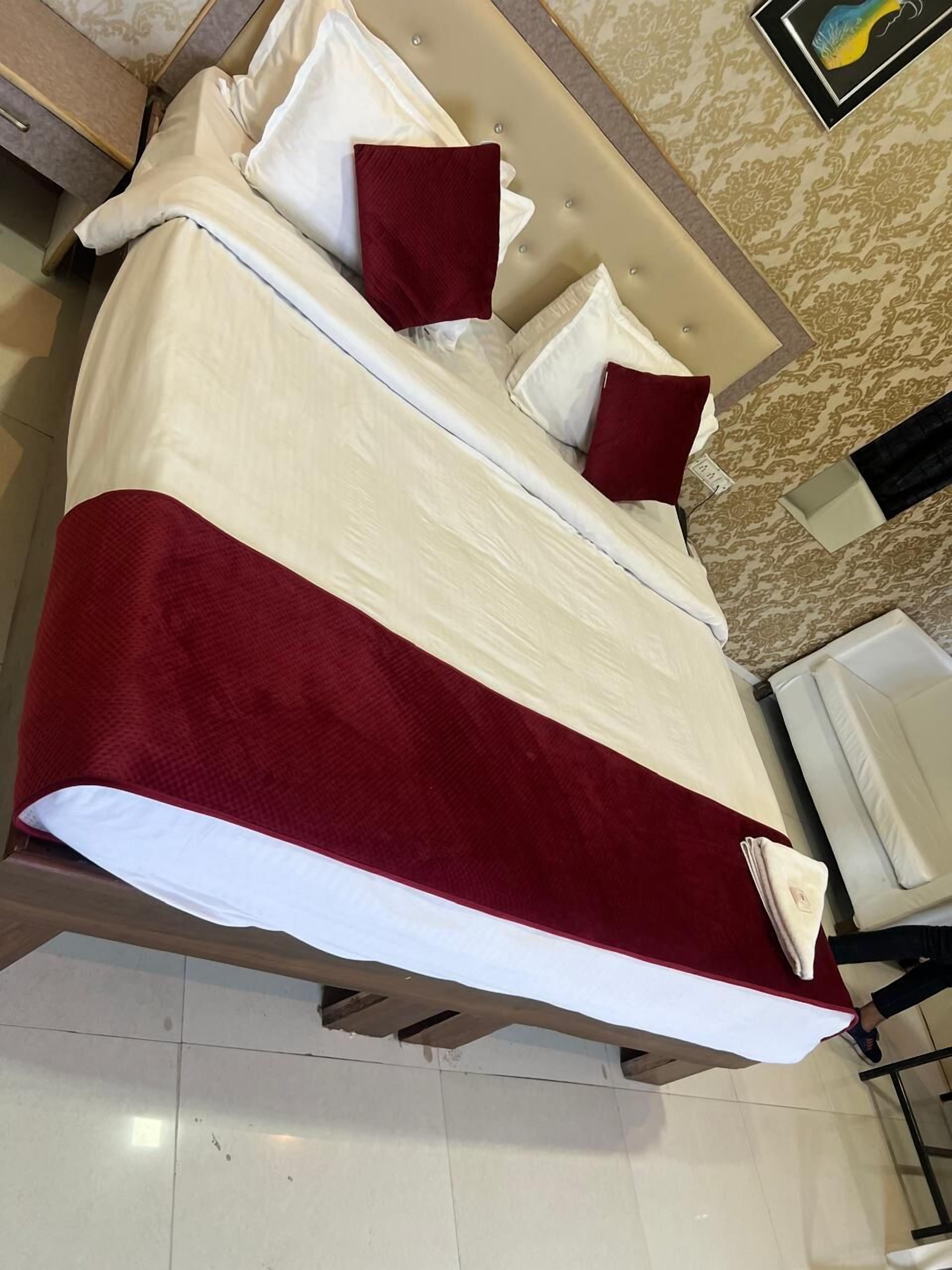 A bed with a white and red bedspread, two red pillows, and a white headboard.