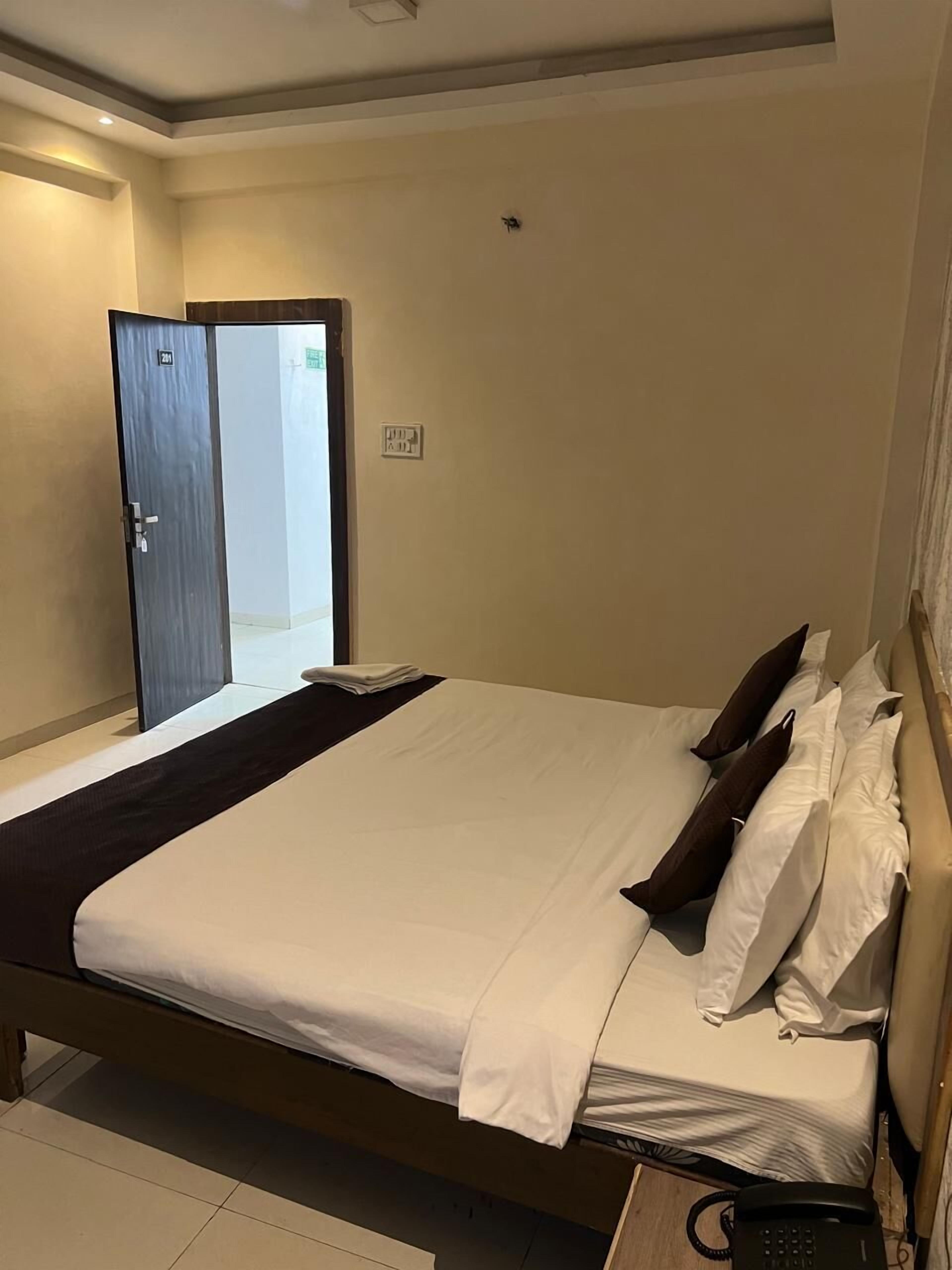Ein Hotelzimmer mit Bett, Nachttischtelefon und einer Tür zu einem Flur.