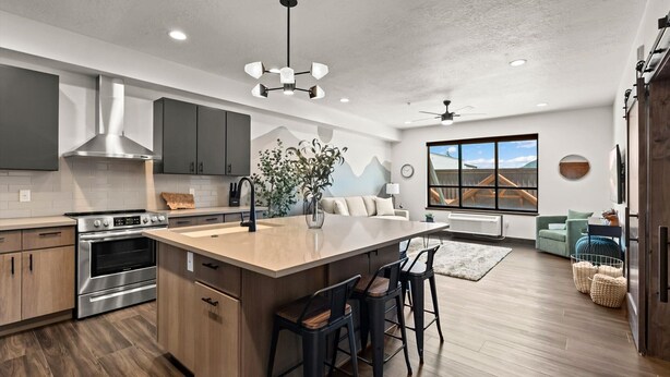 A modern kitchen with a large island, stainless steel appliances, and a farmhouse-style dining area. - Beautiful New Downtown Columbia Falls Condo near Glacier National Park! (Columbia Falls)