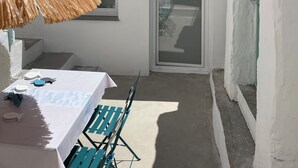 Um pequeno edifício de paredes brancas e telhado em telhas, com uma porta e uma janela.