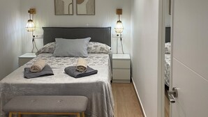 Quarto bem arrumado com cama, mesas de cabeceira, um banco e arte nas paredes.
