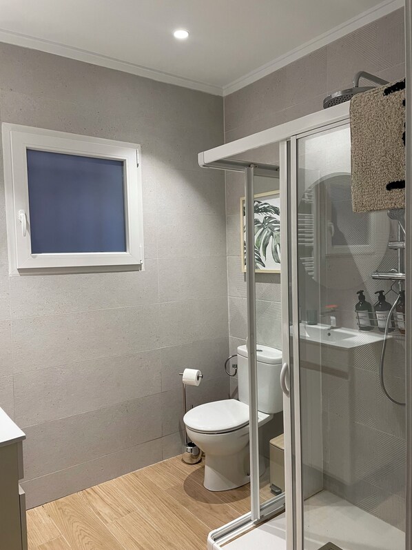 Un baño moderno con inodoro, ducha y ventana.