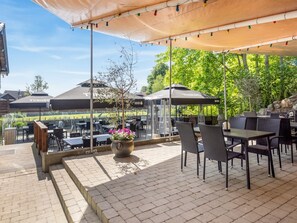 An outdoor patio area with tables and chairs, umbrellas, and a potted plant.