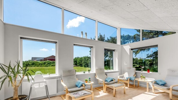 Una habitación moderna y bien iluminada con ventanas amplias, asientos cómodos y una planta en maceta.