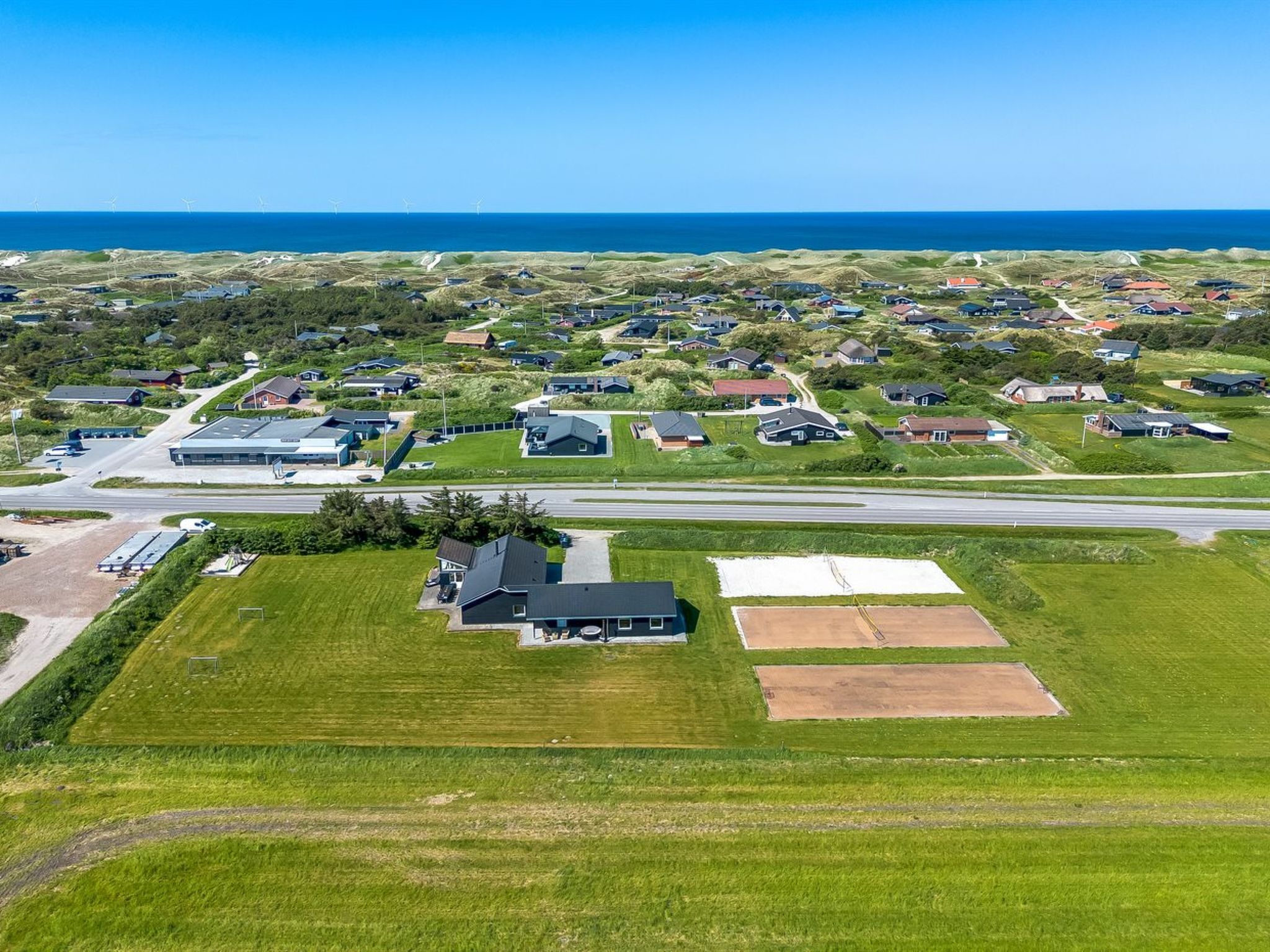 An aerial view of a residential area with houses, a large industrial building, and a road.