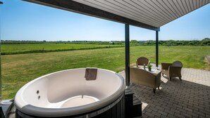 Un jacuzzi bajo una pérgola de madera con vistas a un campo cubierto de césped.