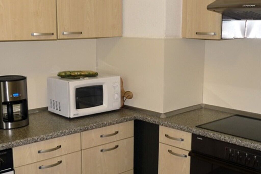 A kitchen with wooden cabinets, a microwave, a coffee maker, and a dishwasher.