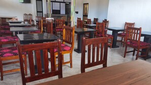 A dining area with wooden tables and chairs, some with pink cushions. - Relais de l'Atakora  (Kpalimé)