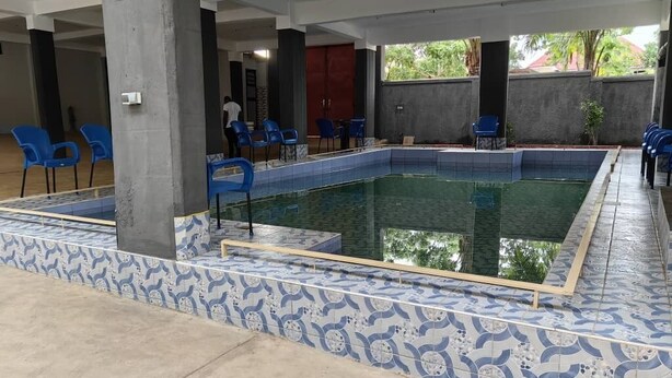 A swimming pool with blue and white patterned tiles, surrounded by blue chairs and a concrete deck. - Relais de l'Atakora  (Kpalimé)