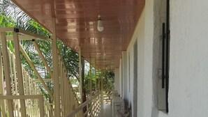 A covered corridor with a tiled floor, a wooden railing, and a red 'Welcome' sign. - Relais de l'Atakora  (Kpalimé)