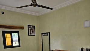 A bedroom with a bed, a ceiling fan, a window, and a picture on the wall. - Relais de l'Atakora  (Kpalimé)