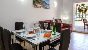 A dining area with a table set for four, a green bottle, and a painting of a coastal scene on the wall. - Agua Blanca by Interhome (Dénia)