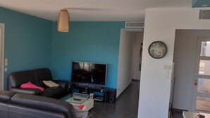 Olohuoneessa on musta nahkasohva, lasinen sohvapöytä ja litteänäyttöinen televisio.
