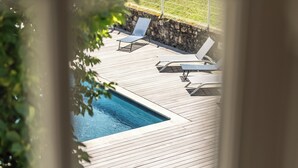 A pool area with lounge chairs and a stone wall.