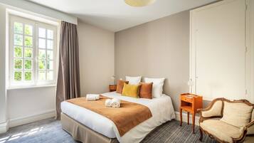 Habitación de hotel con una cama grande, una silla, una mesita de noche y una ventana con cortinas.