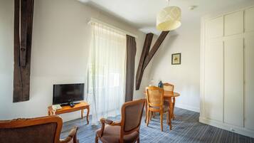 A hotel room with a TV, wooden furniture, a dining table, and a large wardrobe.