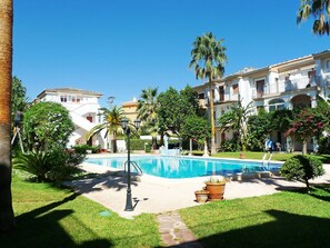 Relax by the pool surrounded by lush greenery and palm trees.