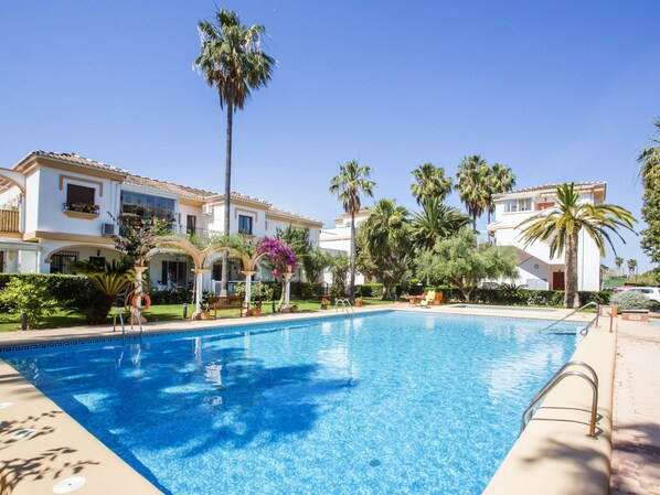 Relax by the resort pool surrounded by lush tropical plants and palm trees.