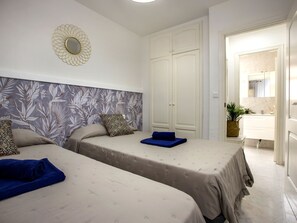 Two single beds with matching headboards, a large wardrobe, and a vanity.