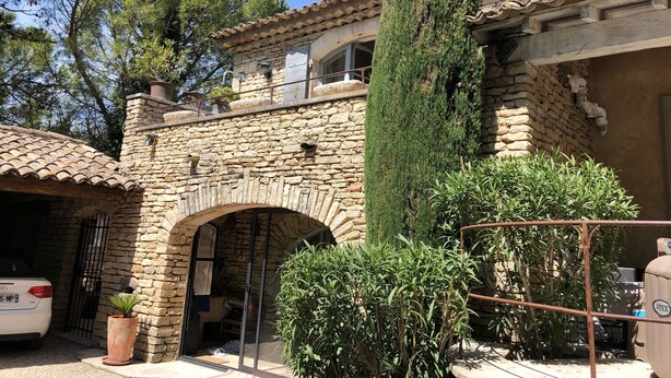 A stone building with a tiled roof, a large tree in front, and a car parked in the driveway. - Au Cœur du Luberon, "l'atelier de La Baronnie" Charme Absolu à 4km de Gordes (Cabrières-d'Avignon)