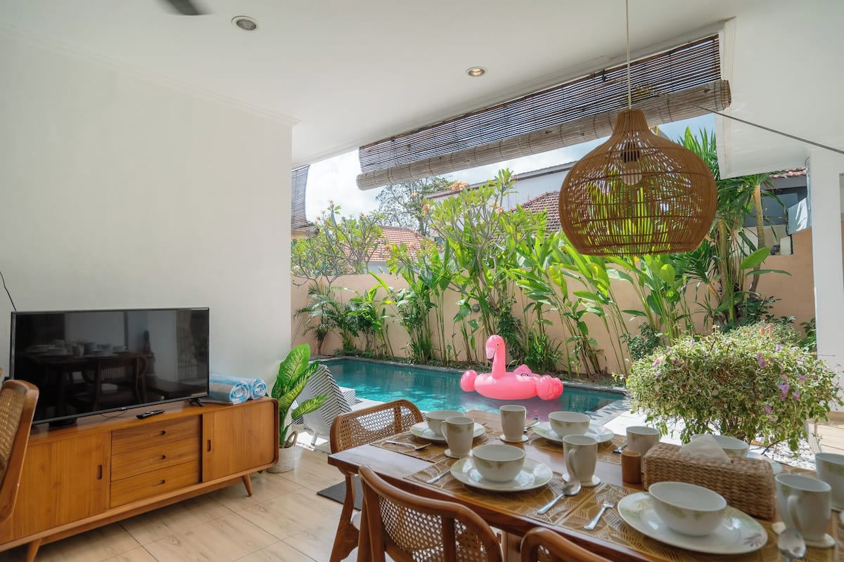 A dining area with a pool, dining set, and a television.