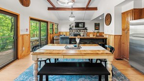 Un comedor amplio con una mesa y sillas de madera, una gran lámpara de araña y una chimenea de piedra.