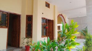 A corridor with wooden doors and windows, potted plants, and a tiled floor. - Star Residency (Varanasi)