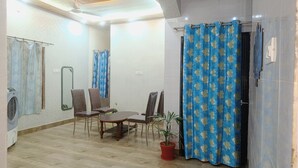 A room with a dining table, four chairs, a potted plant, and a shower curtain. - Star Residency (Varanasi)