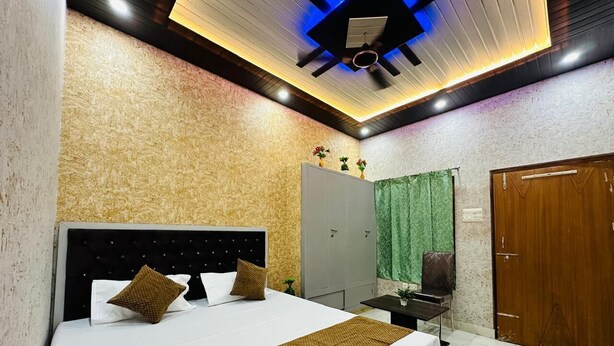 A modern bedroom with a large bed, a ceiling fan, and a wardrobe. - Star Residency (Varanasi)