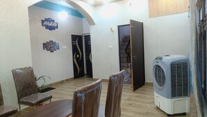 A dining area with a table and chairs, a wall-mounted air conditioner, and a door leading to another room. - Star Residency (Varanasi)