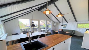 A modern kitchen with a wooden countertop and sink, a dining area with a table and chairs, and a seating area with a couch and a small table. - "Antonelle" - 1.7km from the sea by Interhome (Blåvand)